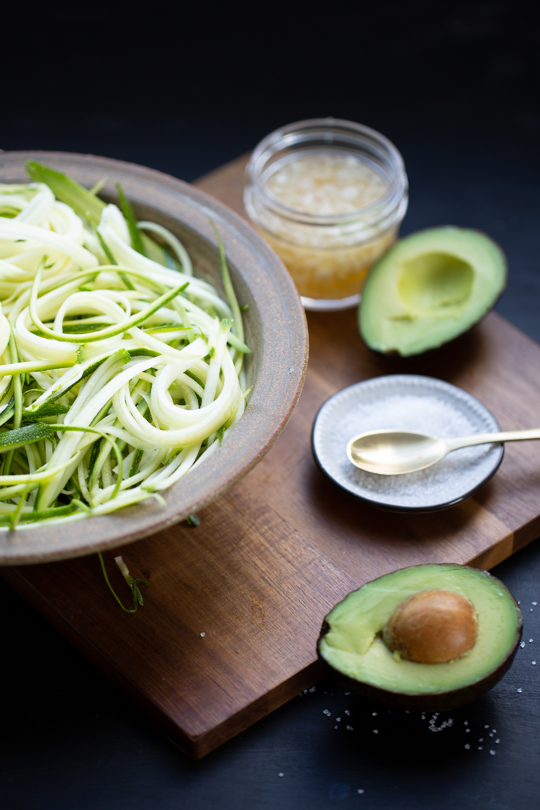 julinned zucchini in a bowl with an avocado on the side