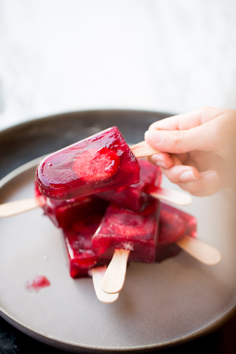 a kids hand grabing a strawberry hibiscus paleta