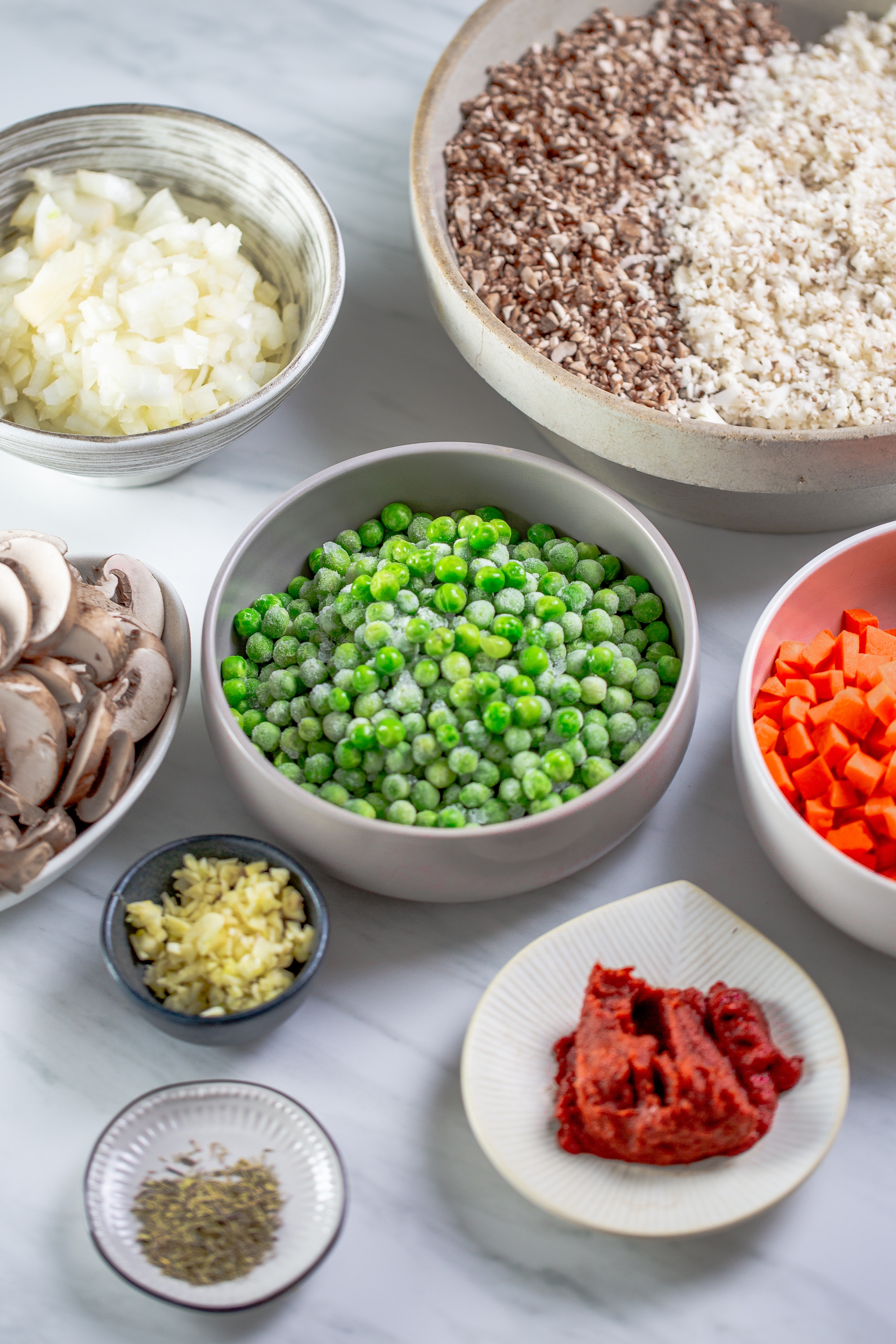 Bowl of peas, carrots, tomatoe paste, chopped garlic, and mushroom cauliflower meat.