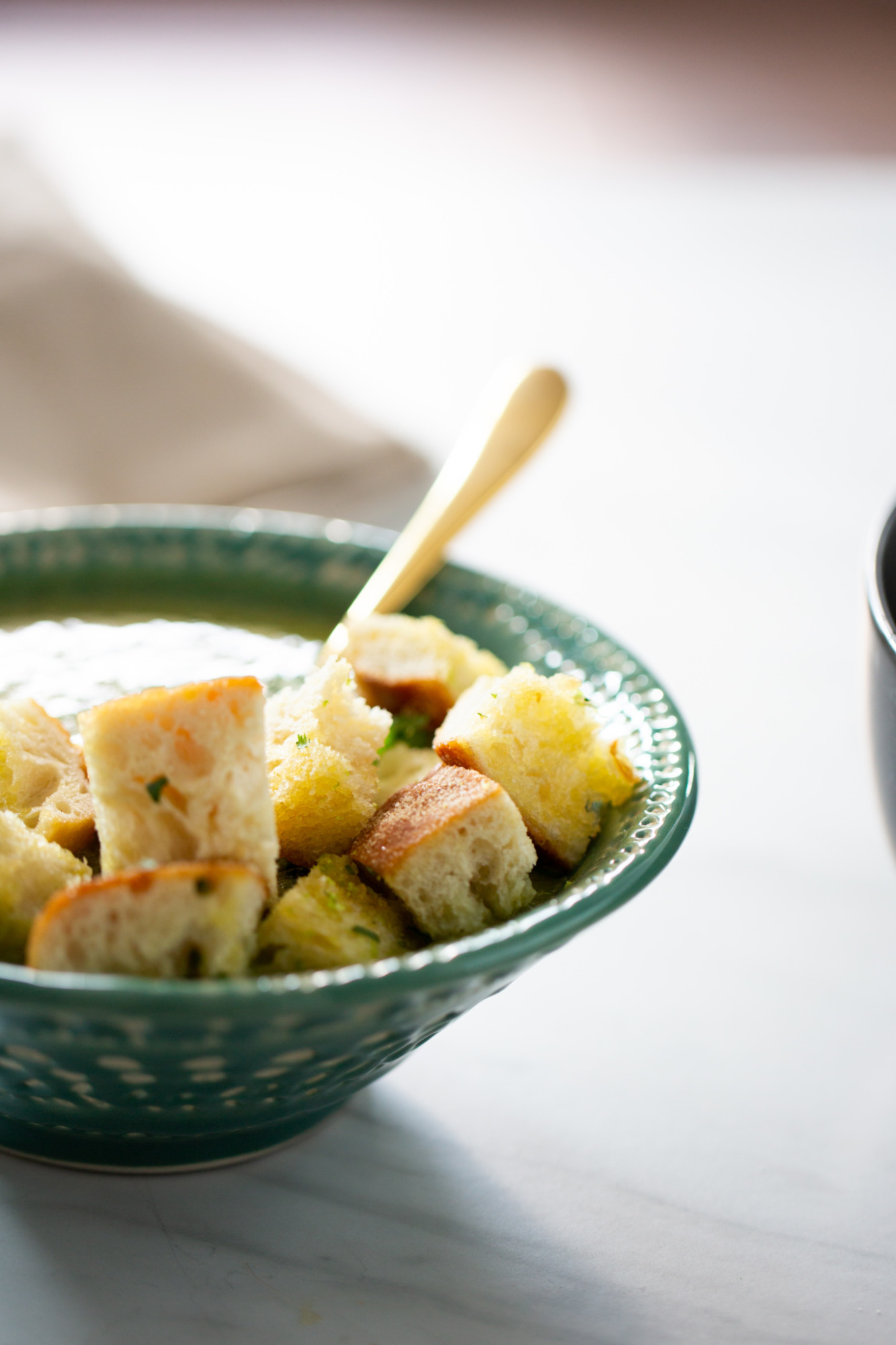 a bowl of broccoli and spinach soup with croutons