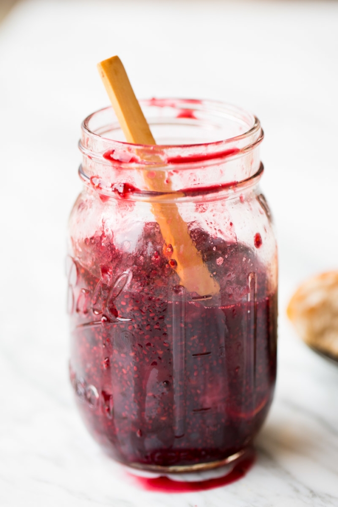 Berry chia seed jam in a jar with a wooden spoon inside