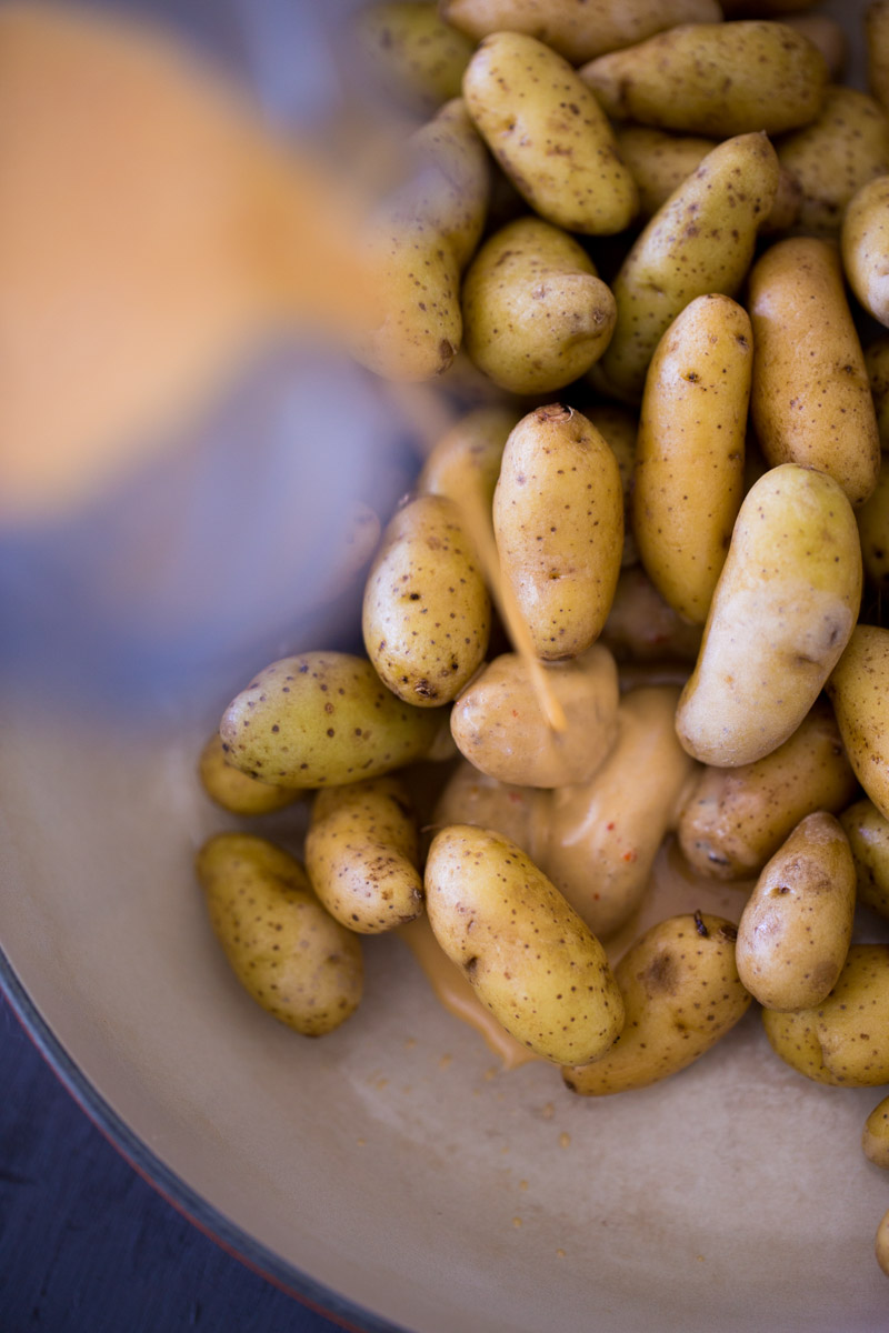 pouring the dressing over the samll potatoes.