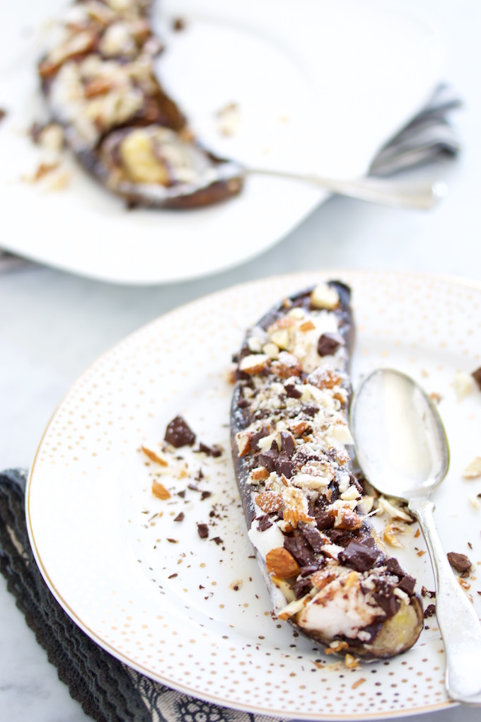 Vegan S'mores Banana Boats on a white dish with a silver spoon on the side