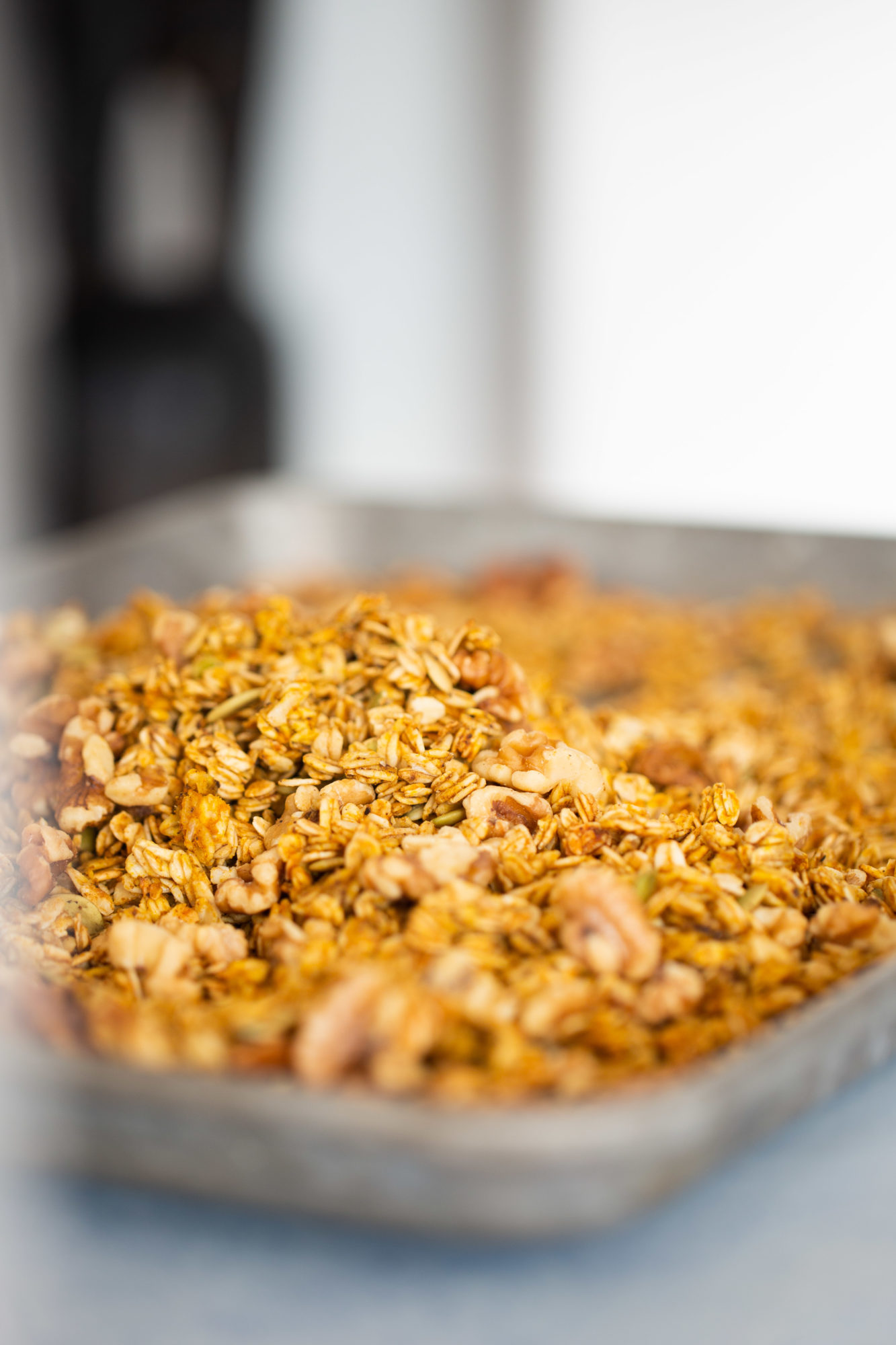 baked granola in a bakin sheet with walnuts and pepitas.