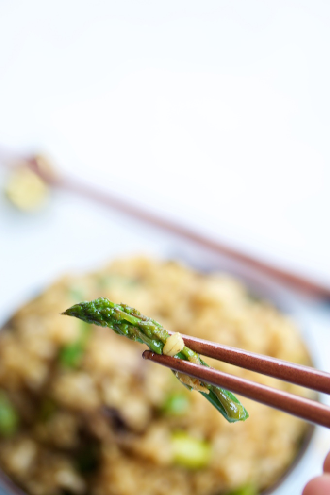 chopsticks holding an asparragus tip.