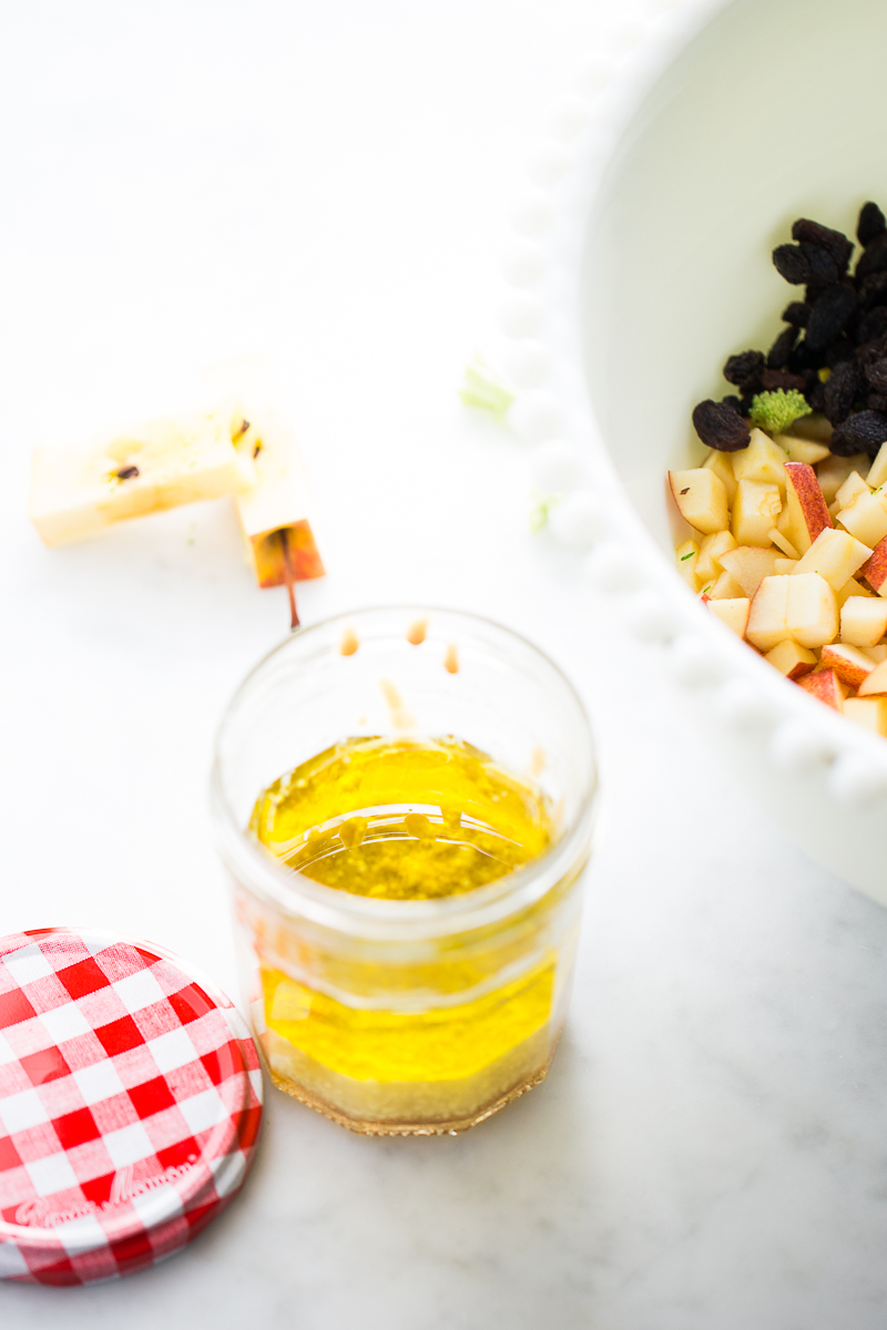 Vinaigrette in a jar next to the bowl with chopped apples and raisins