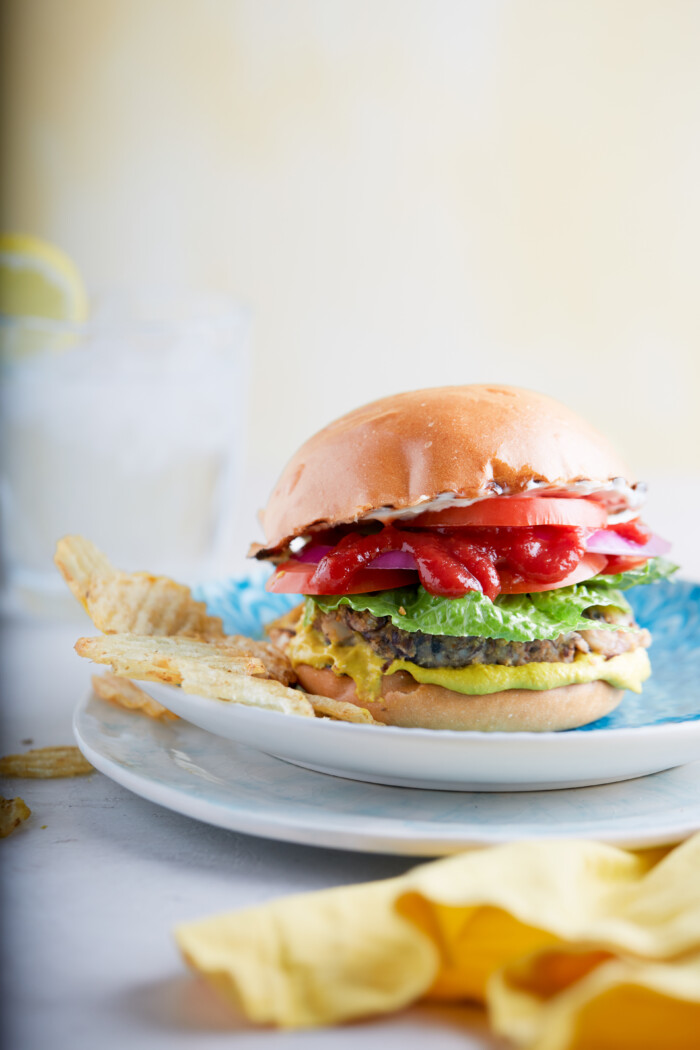 hamburguesa vegana hecha en casa con ketchup, tomates, lechuga y papas fritas a un lado