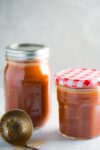 A jar of homemade enchilada sauce and a spoon next to it.