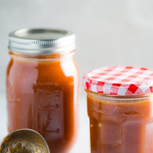 A jar of homemade enchilada sauce and a spoon next to it.