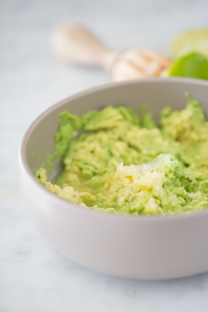 Guacamole with crushed garlic in a grey bowl.