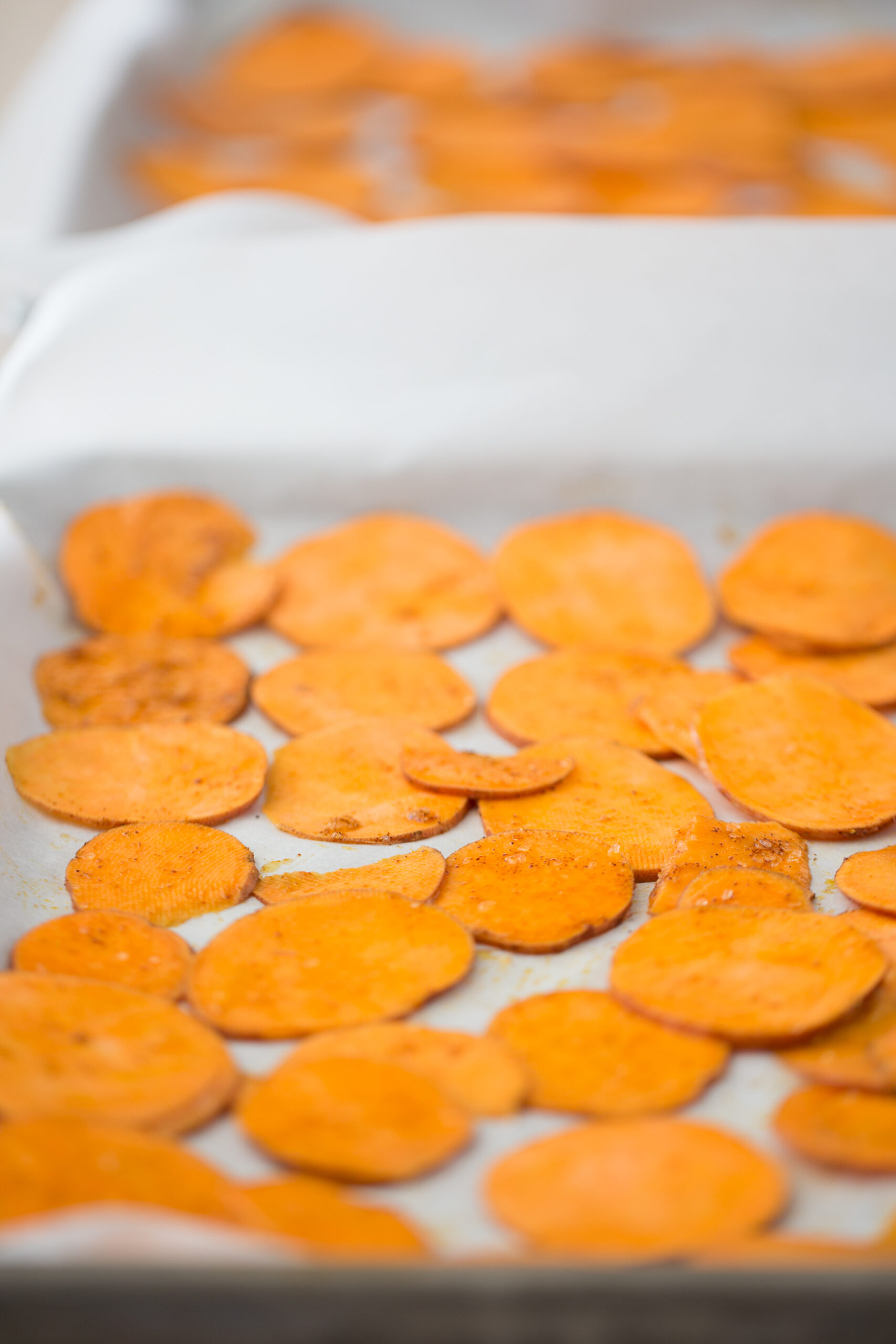 Sliced sweet potatoes on a baking sheet.