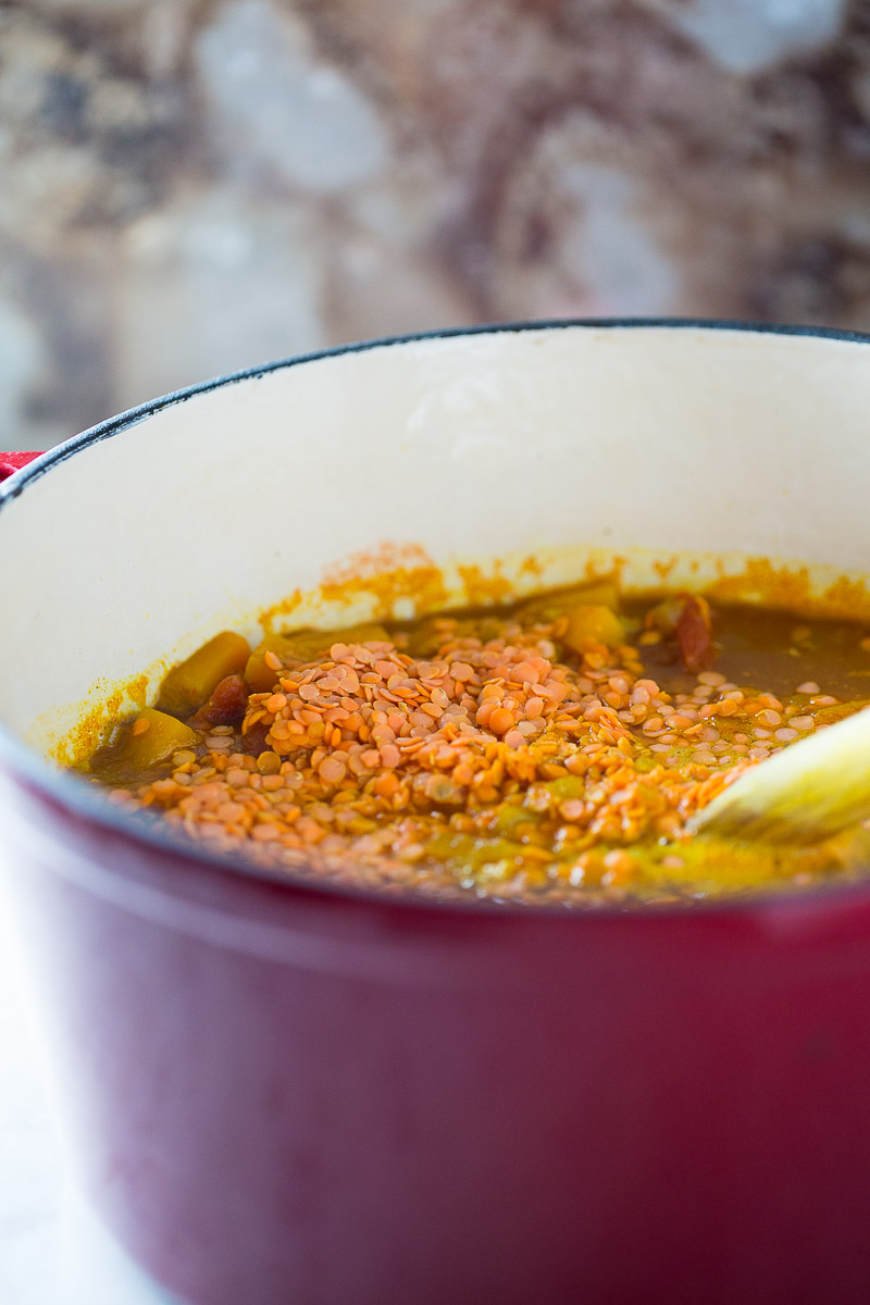 vegan red lentil soup cooking in a red dutch oven