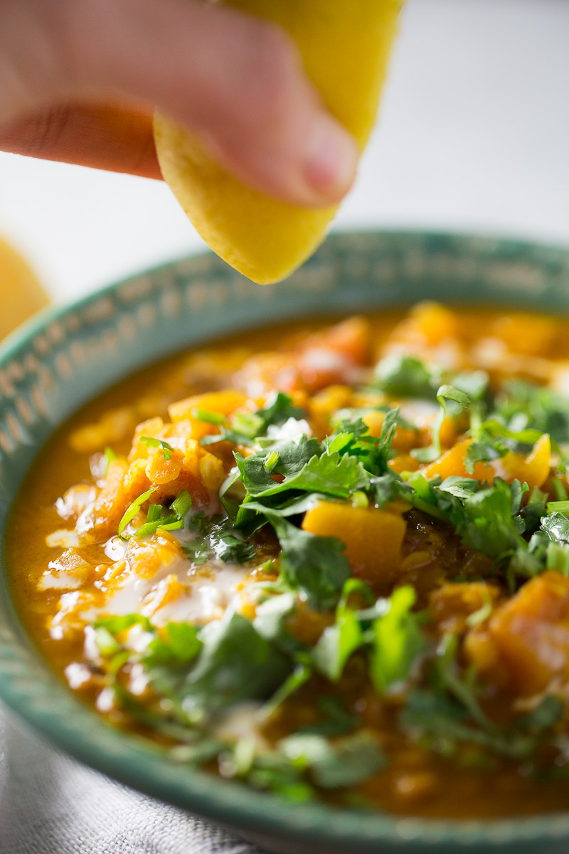 Adding some freshly squeezed lemon juice to a bowl of curried red lentil soup