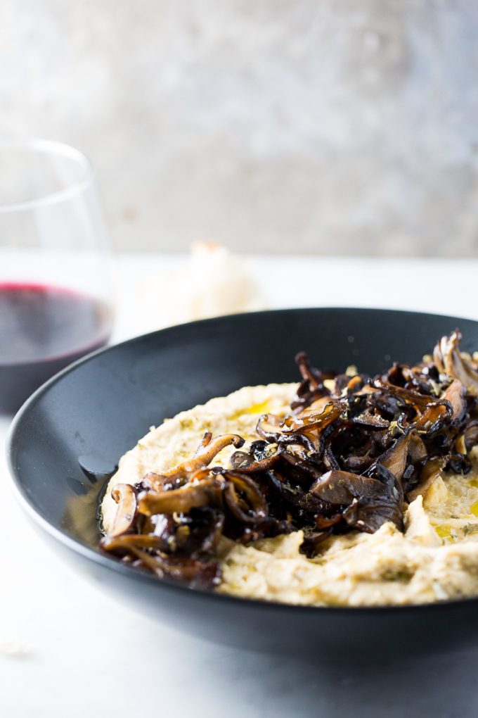 hummus with mushrooms and a glass of wine in the back