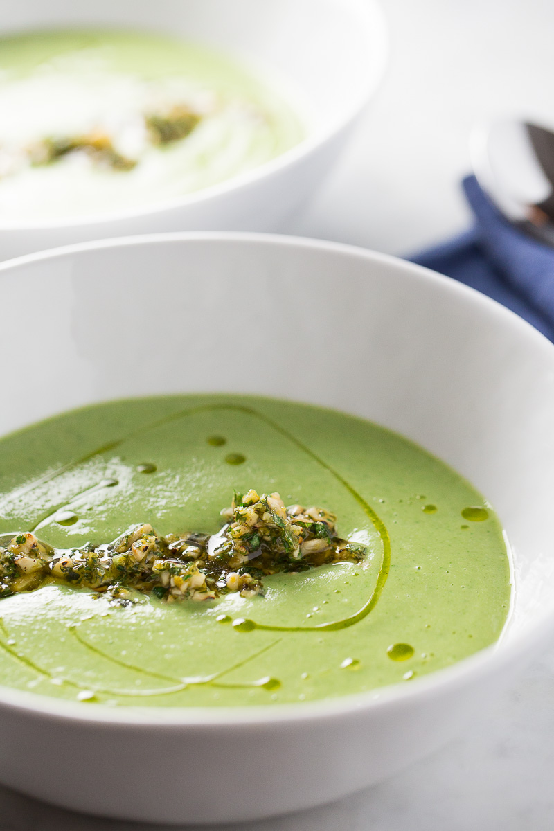 Creamy broccoli soup topped with chopped cashews with basil and drizzled with olive oil