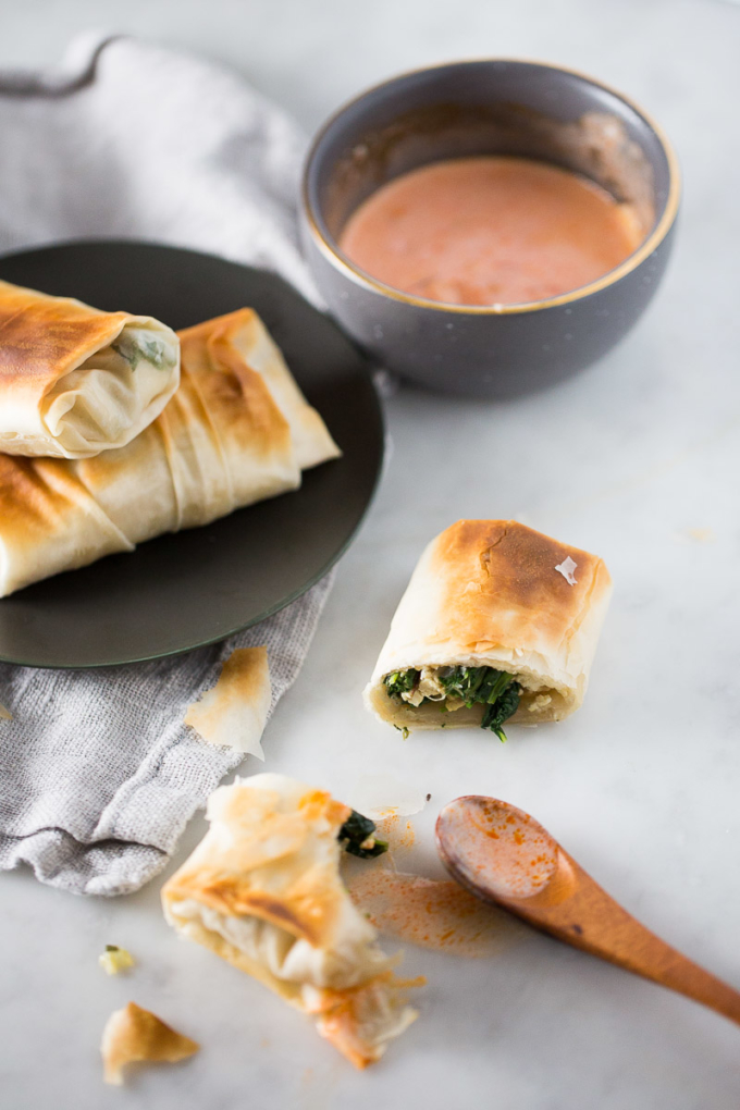 Spanakopita rolls, vegan on a plate and with pink sauce on the side.