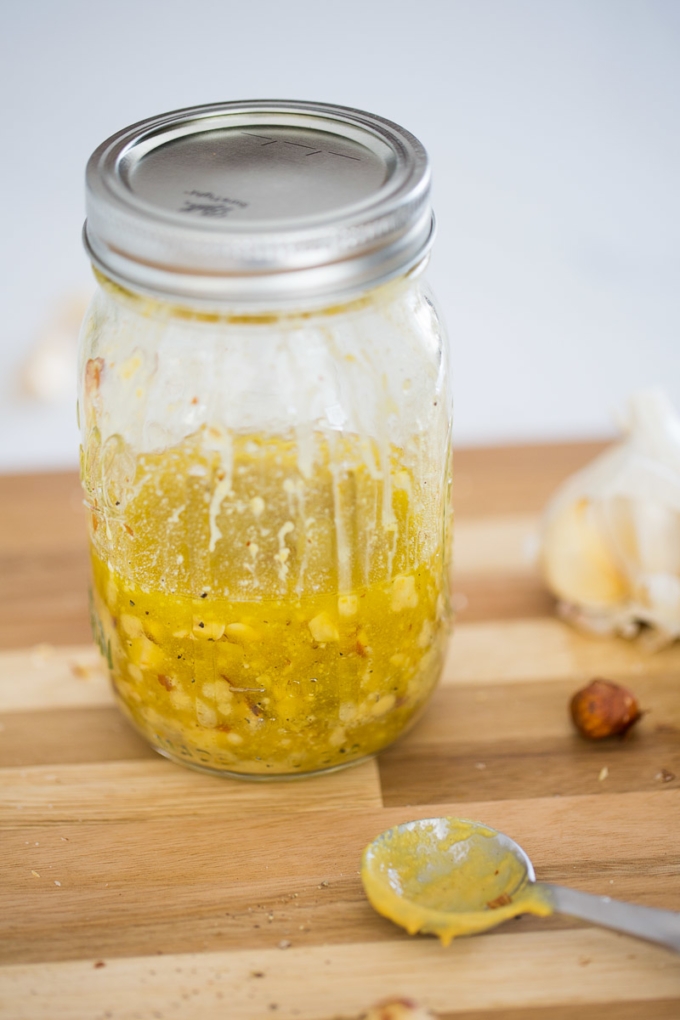 A jar of simple vinaigrette on a cutting board.