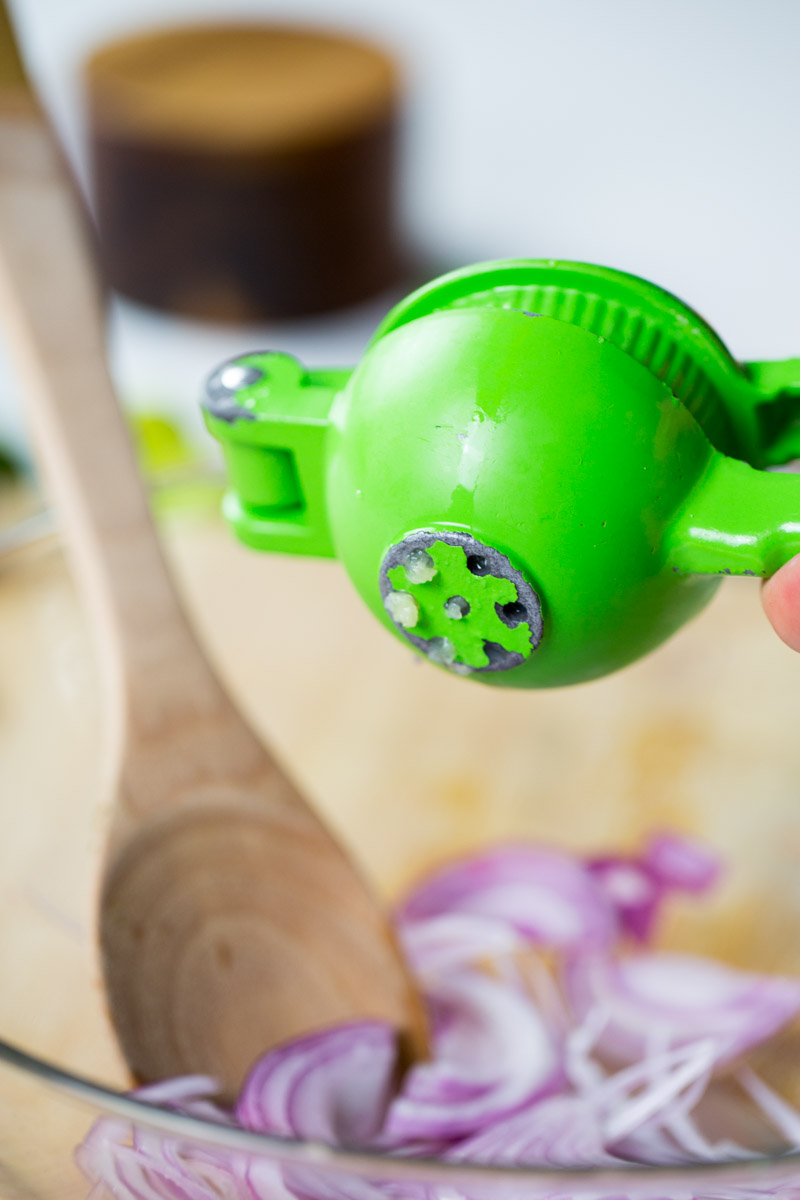 using a lime press to squeeze lime over red onion