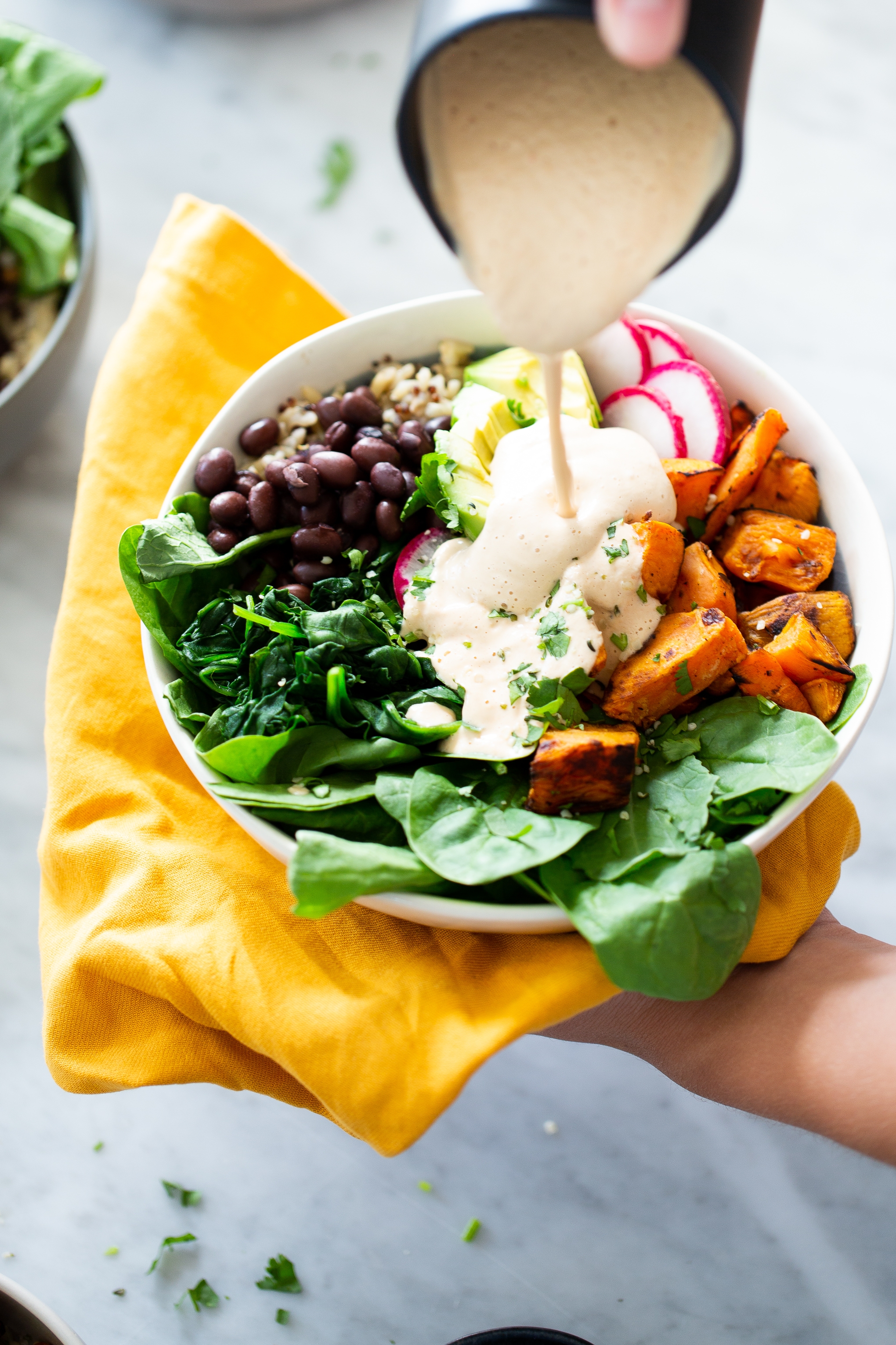 Roasted sweet potato Mexican Buddha bowl with cashew chipotle dressing being poured over