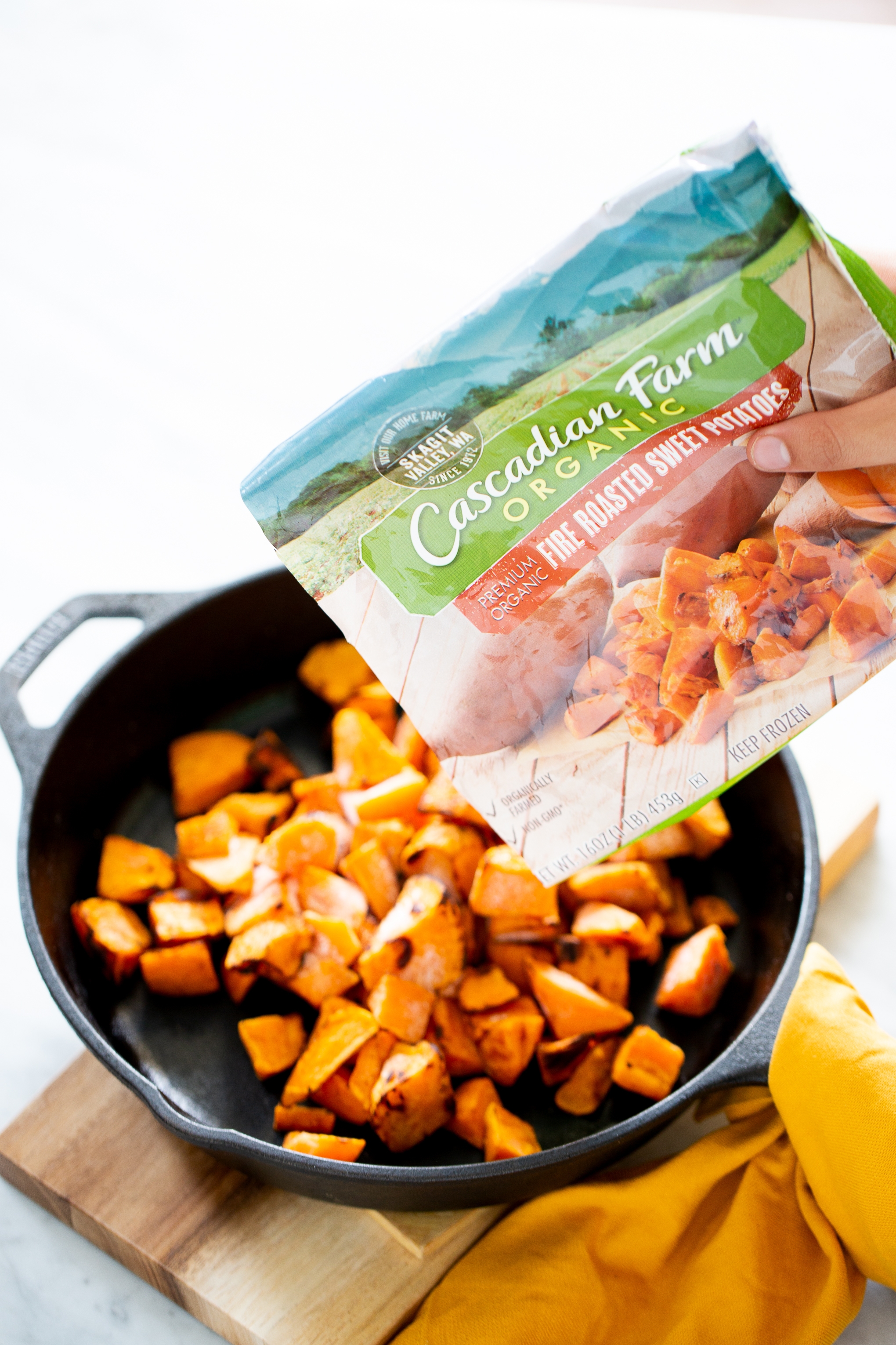 Adding roasted sweet potatoes to a skillet