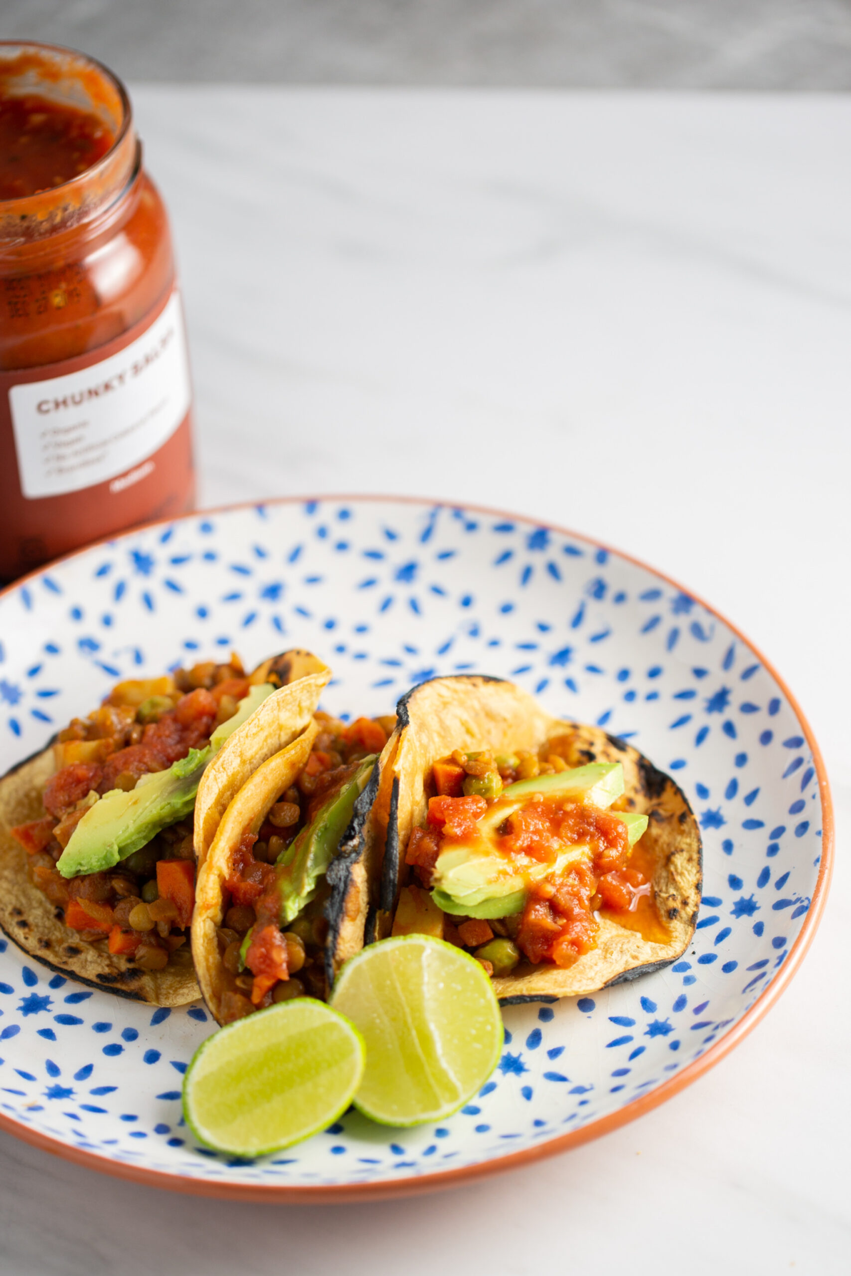 Three Mexican vegan picadillo corn tortilla tacos with avocado and salsa.