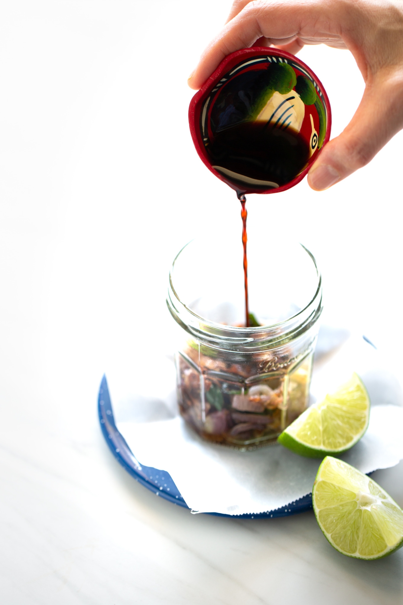 Chiles toreados with blistered serrano peppers and onion in a glass jar.