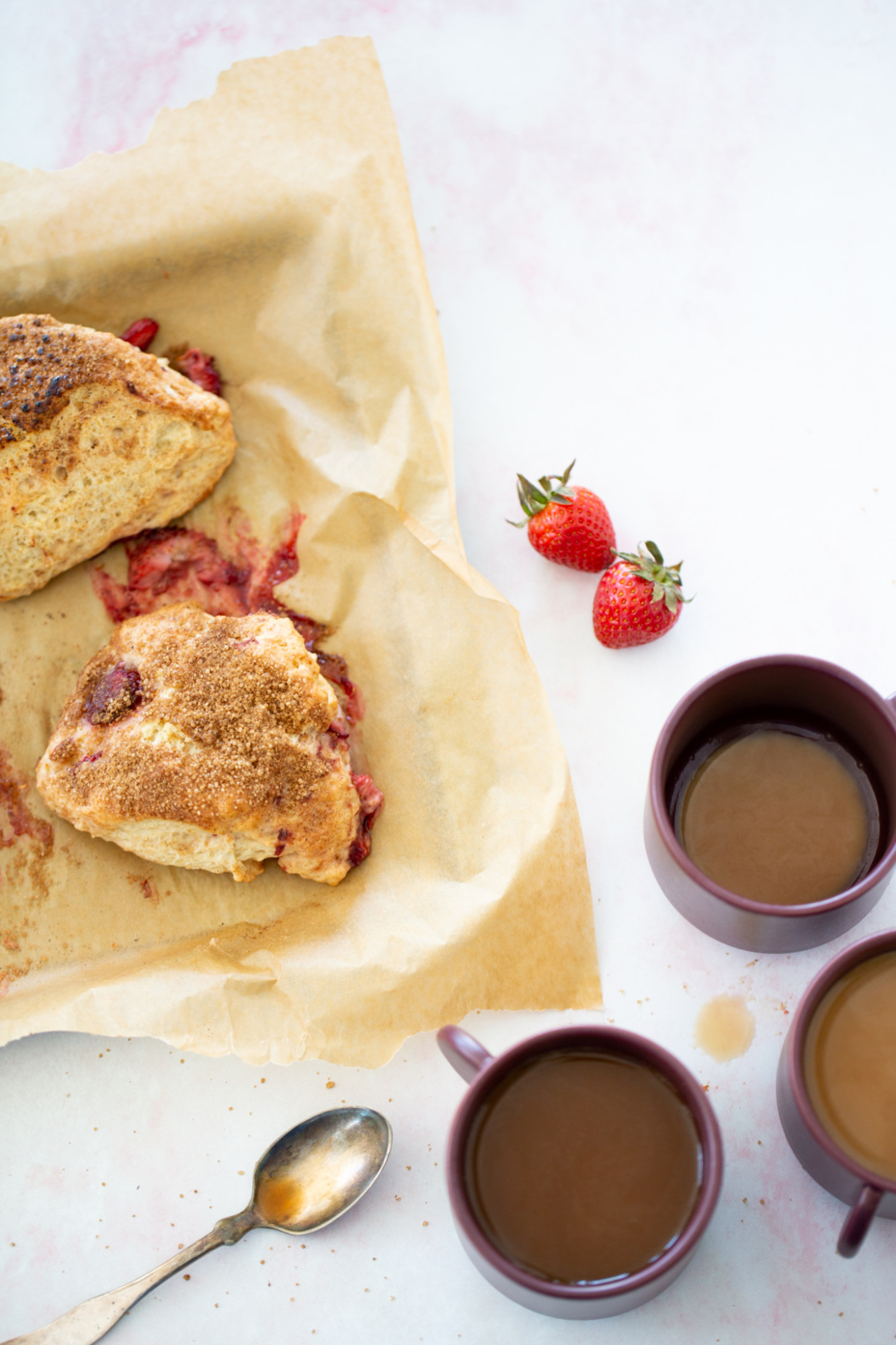 vegan strawberry scones on a baking sheet with three cups of coffee