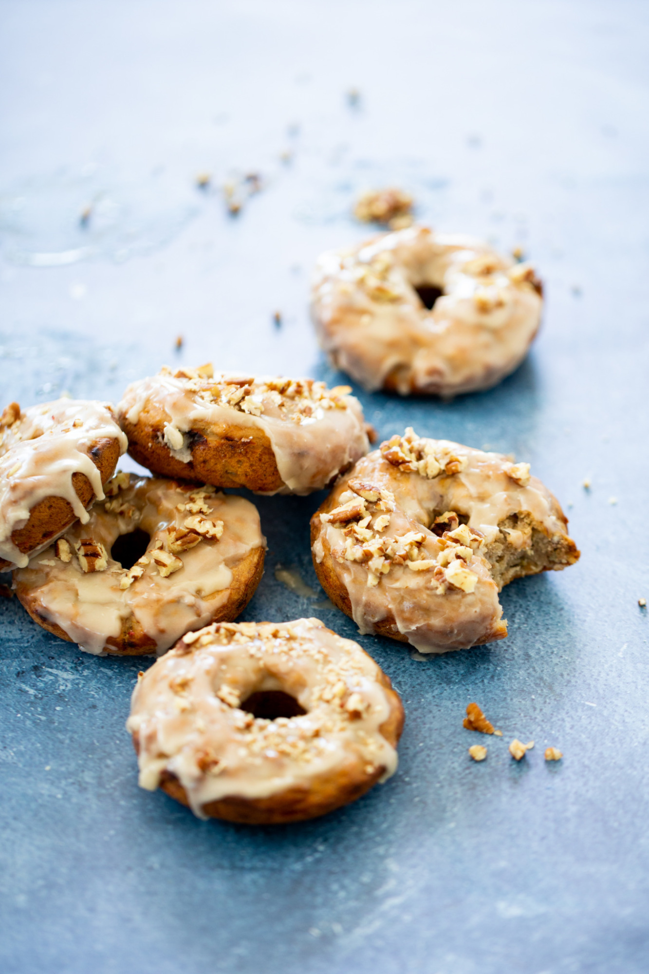 baked vegan banana donuts with maple glaze and sprinkled chopped walnuts