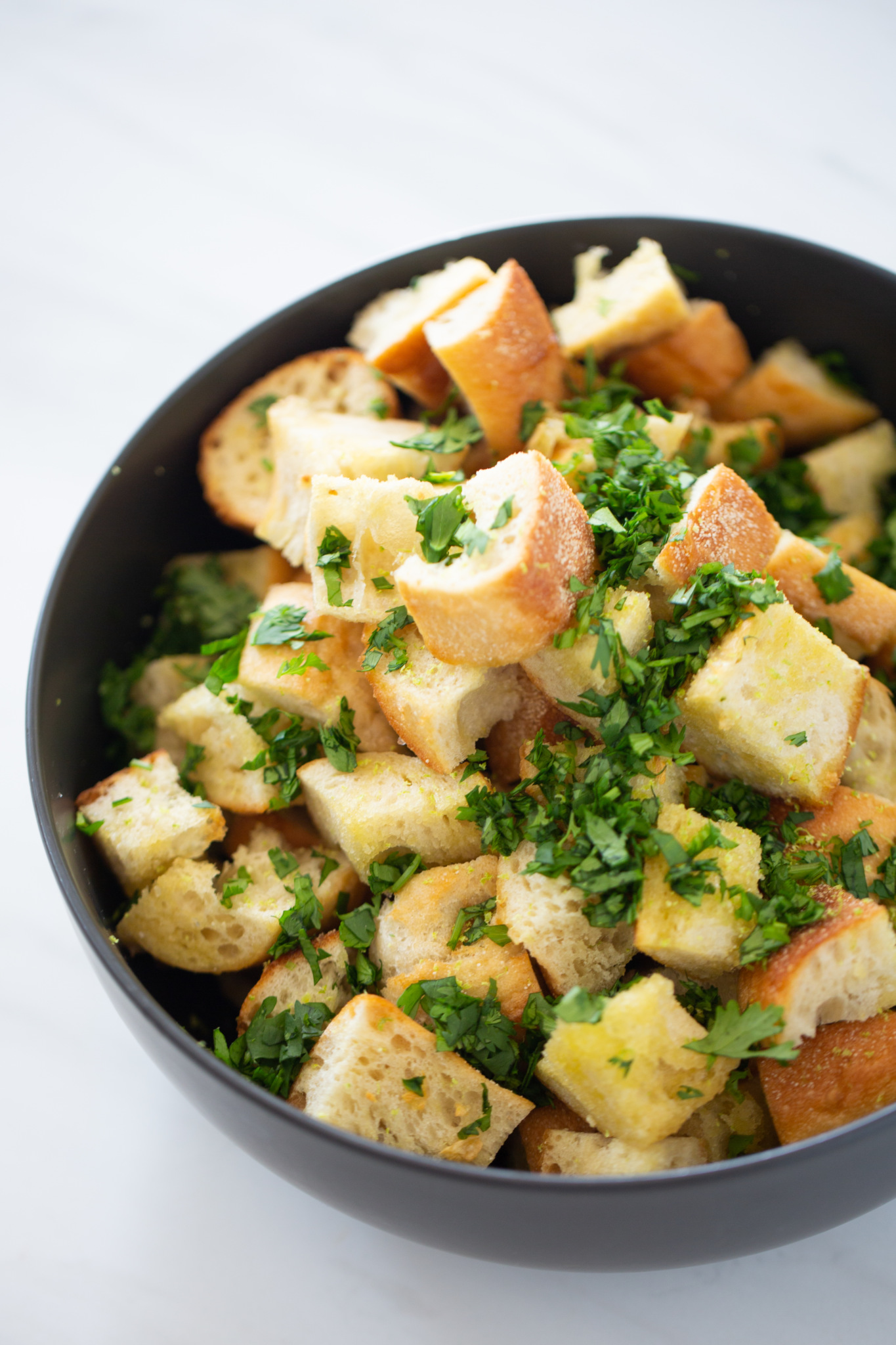 A bowl of broccoli and spinach soup garnished with chopped parsley.