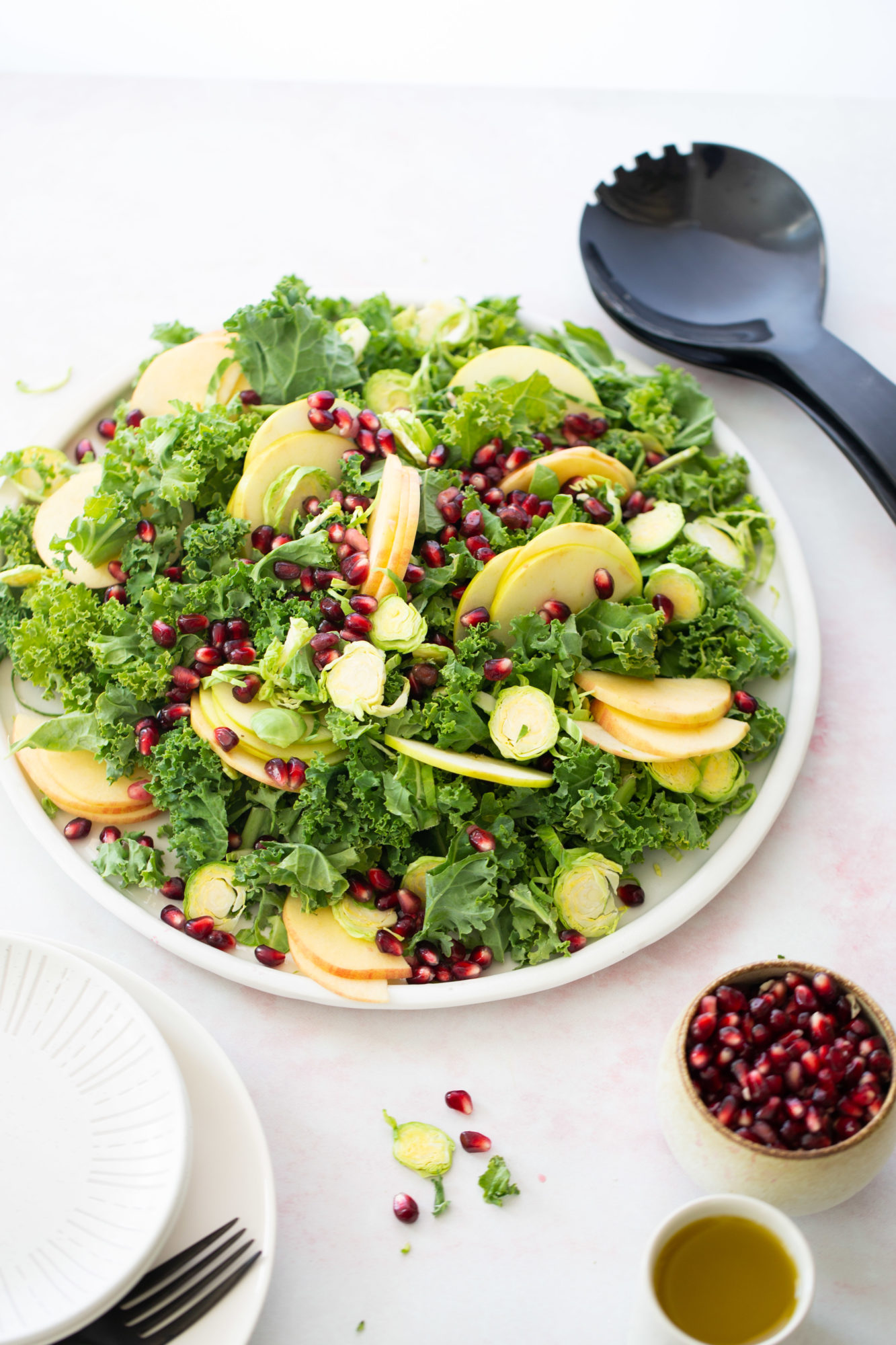 A plate of kale salad with apples and pomegranate.