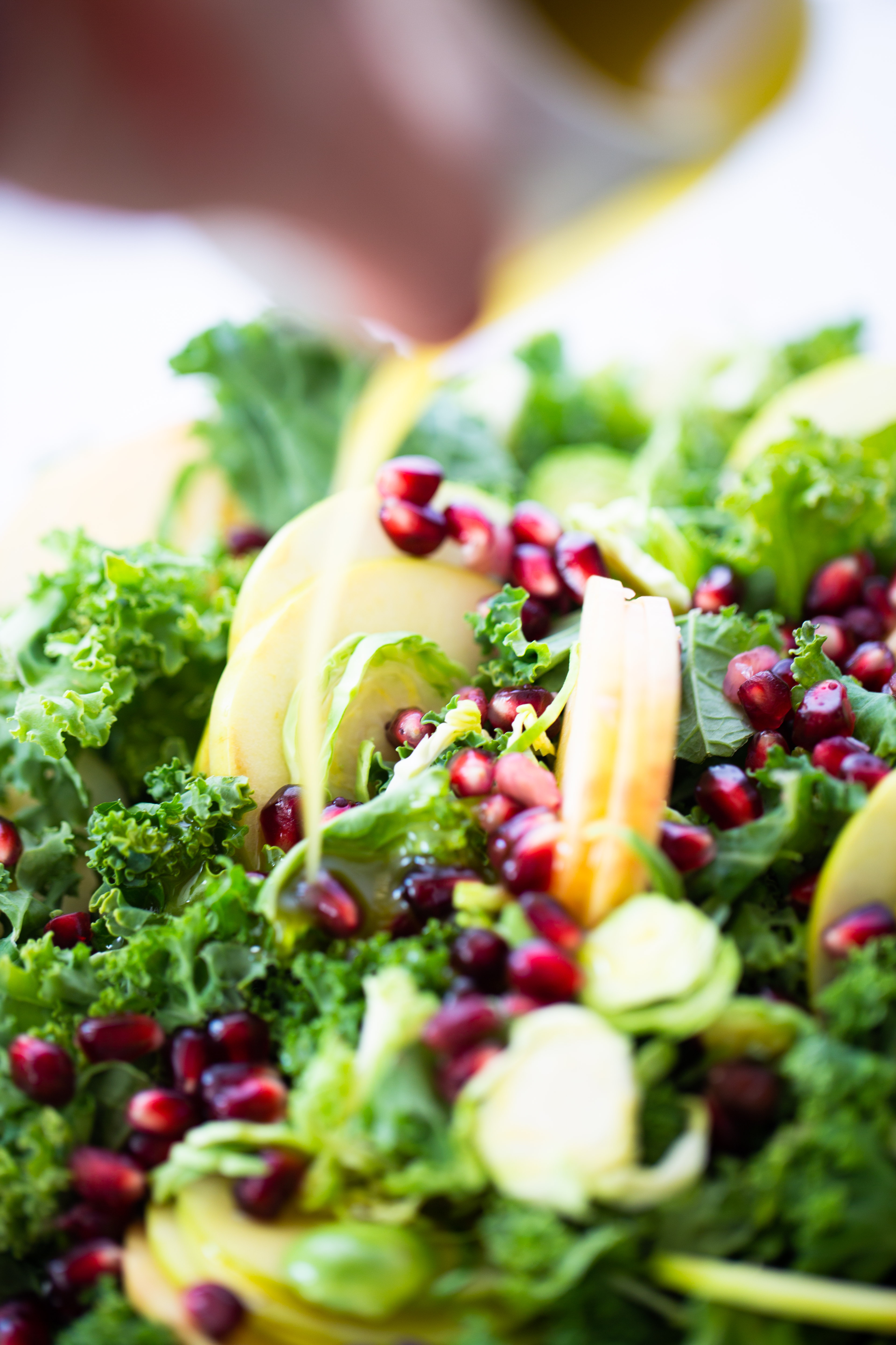 A person is pouring olive oil on a brussels sprouts salad.