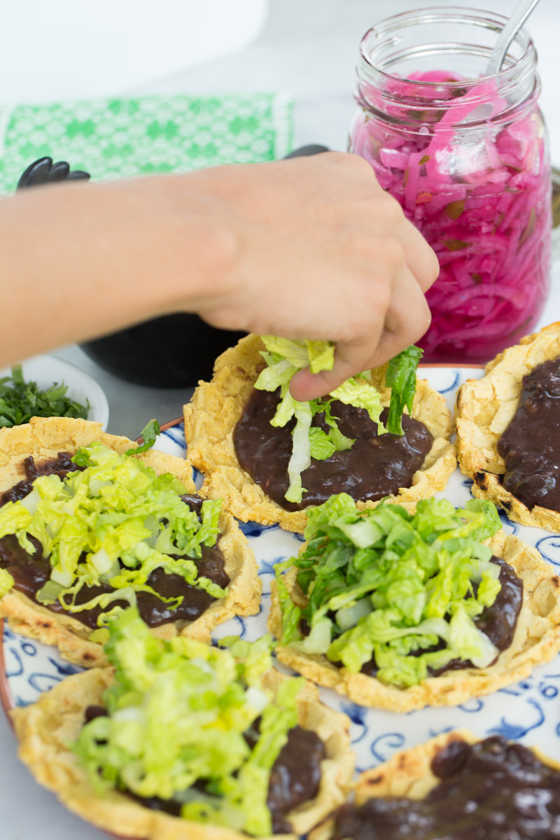 finishing sopes with shredded lettuce