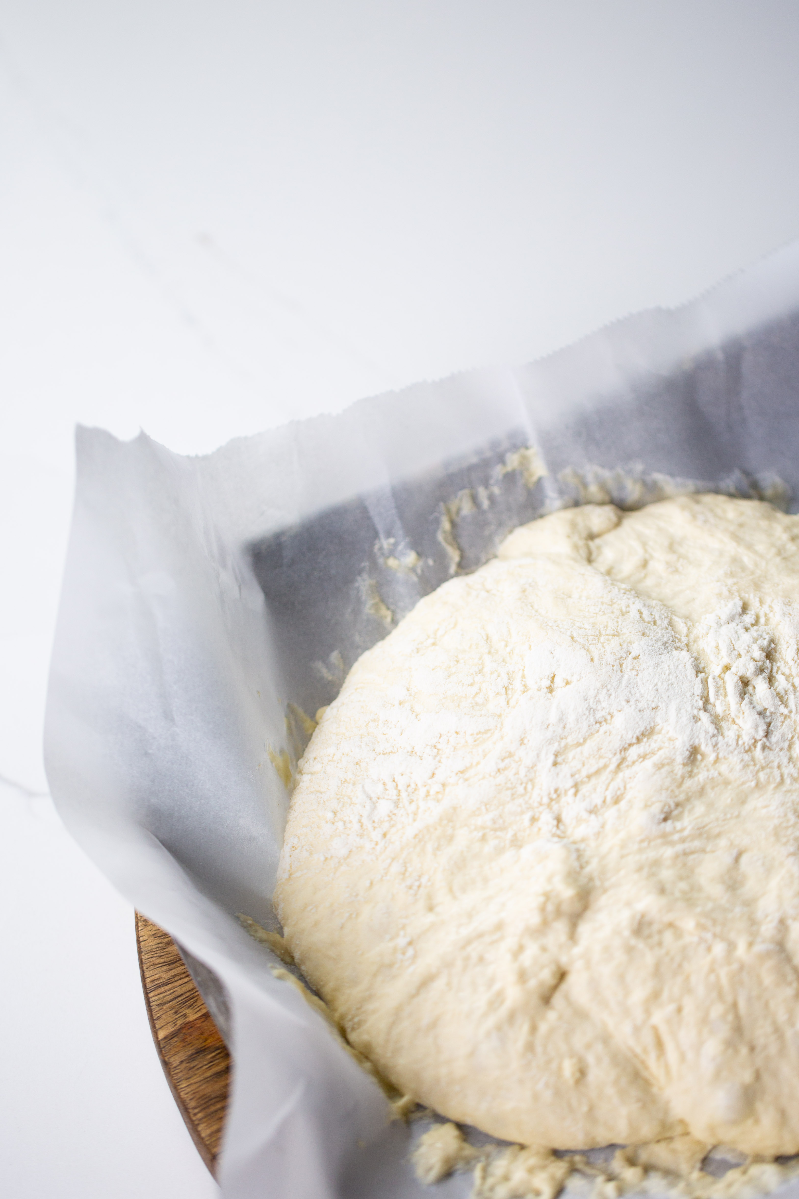 A bowl of dough on a wooden board.