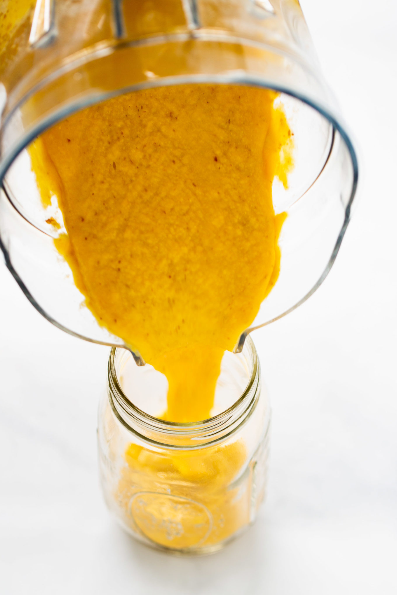 Pouring vegan queso to a jar from the blender