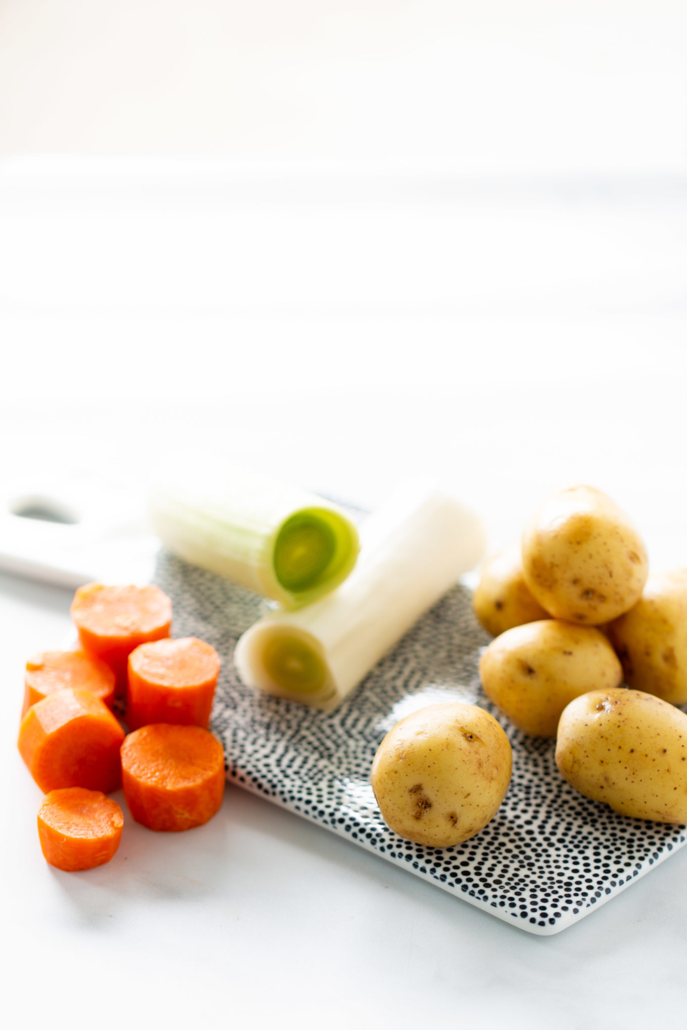 Potatoes, carrots and lek on a ceramic cutting board