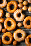 Vegan glazed donuts on a cooling rack.