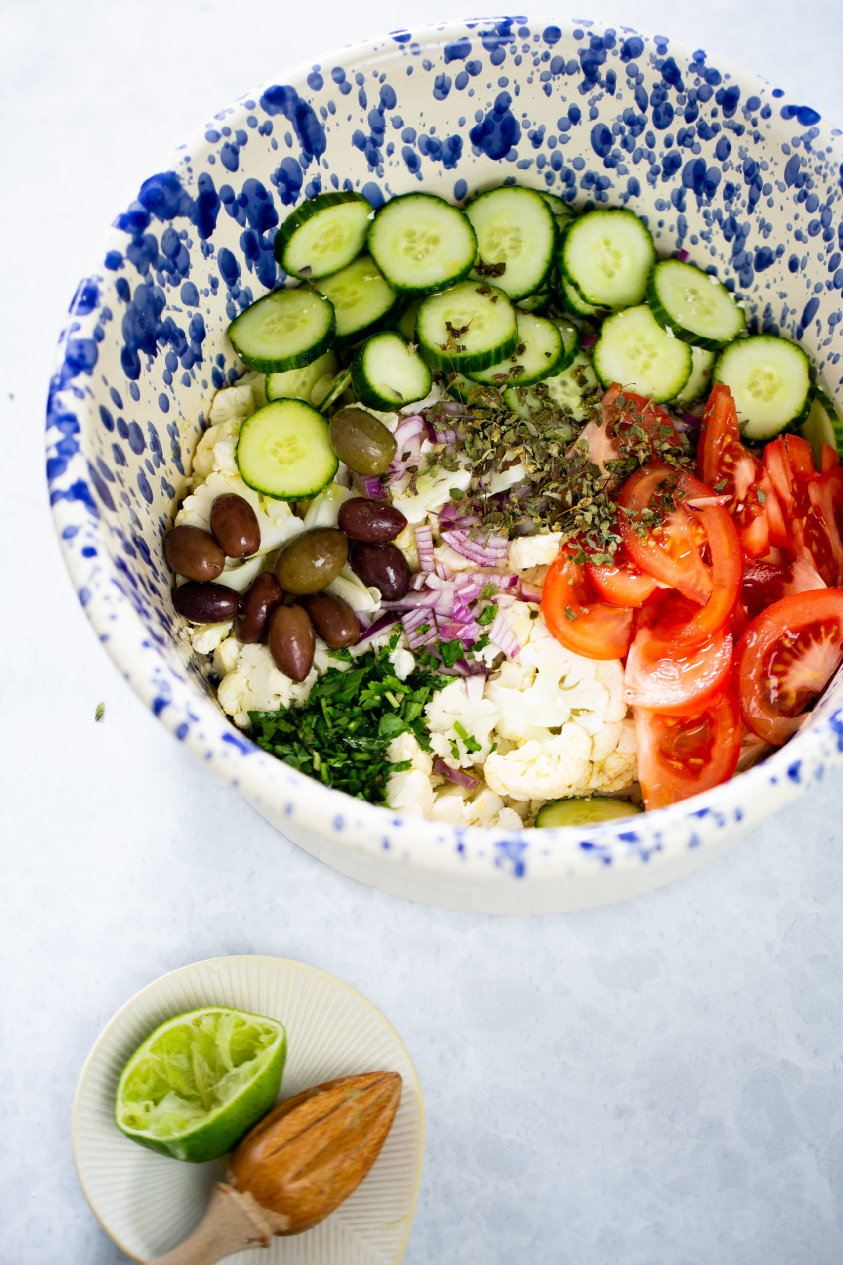 ingredientes para hacer ensalada de coliflor mediterranea en una ensaladera antes de ser revueltos.