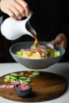 Sauce being poured over tacos dorados