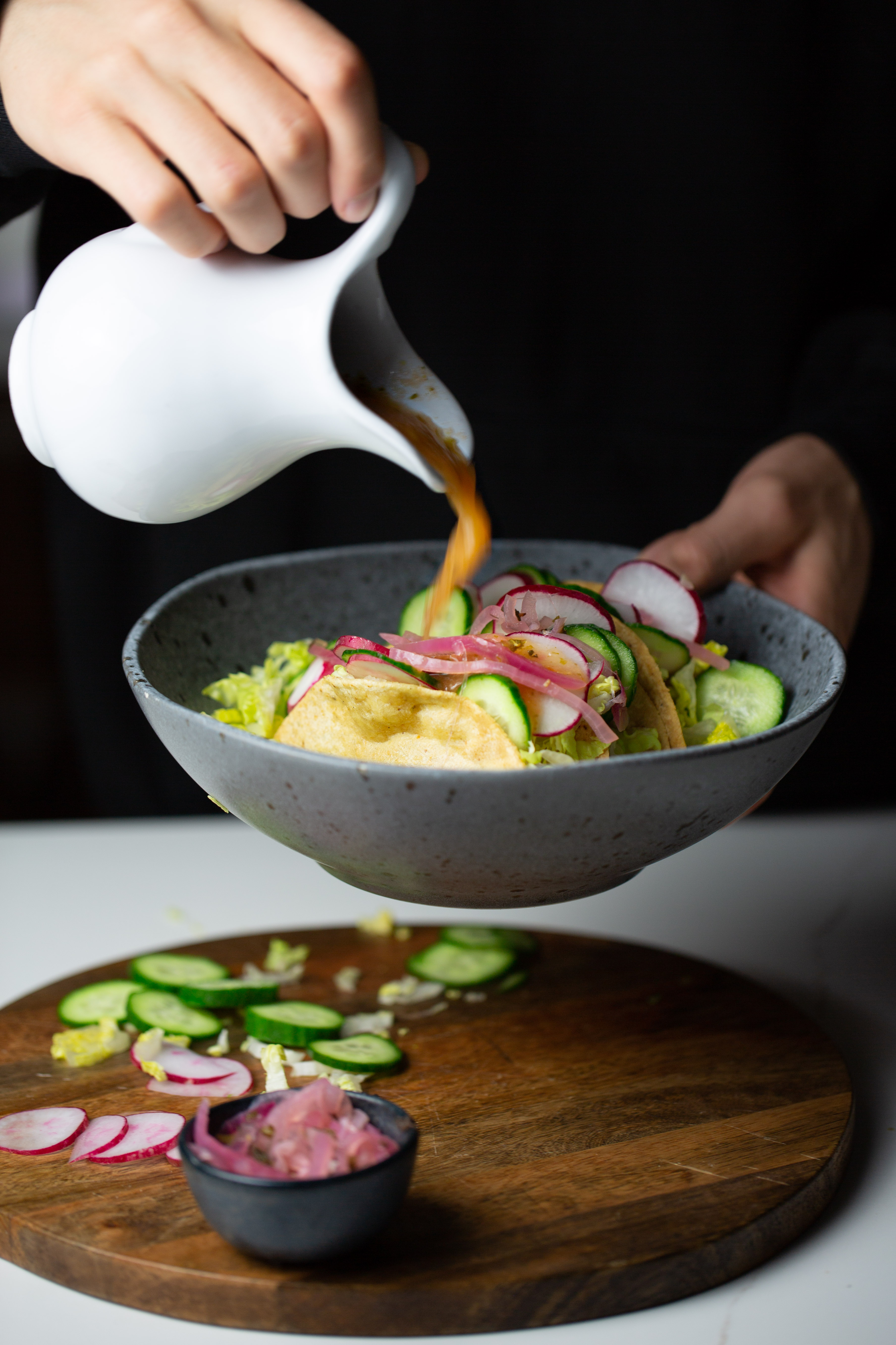 Sauce being poured over tacos dorados
