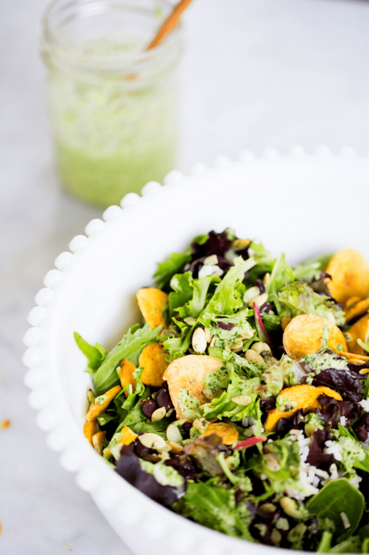 A white bowl with a salad in it drizzled with cilantro dressing.