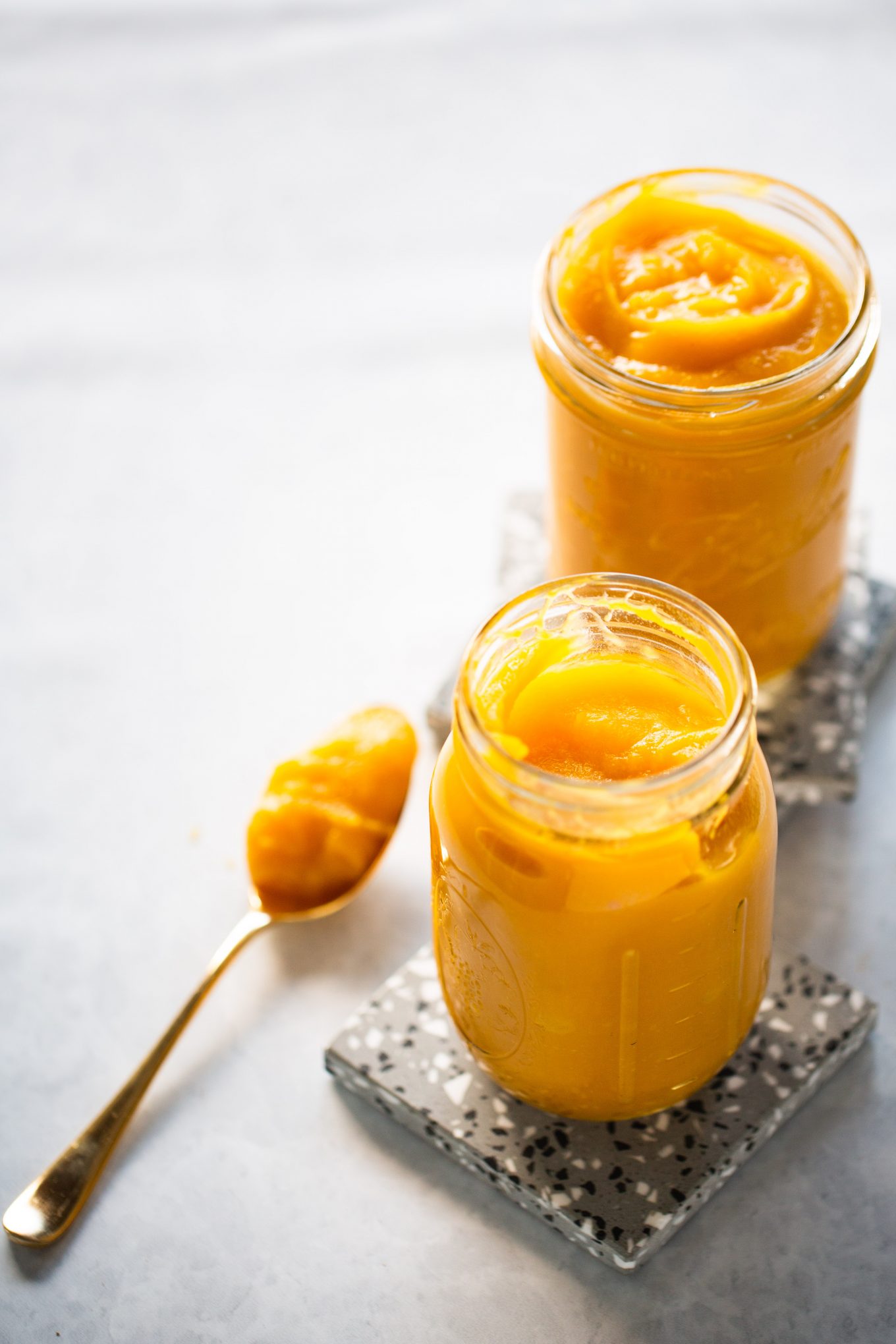 Two jars of homemade pumpkin puree sitting on a table.