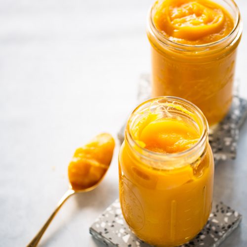 Two jars of homemade pumpkin puree sitting on a table.