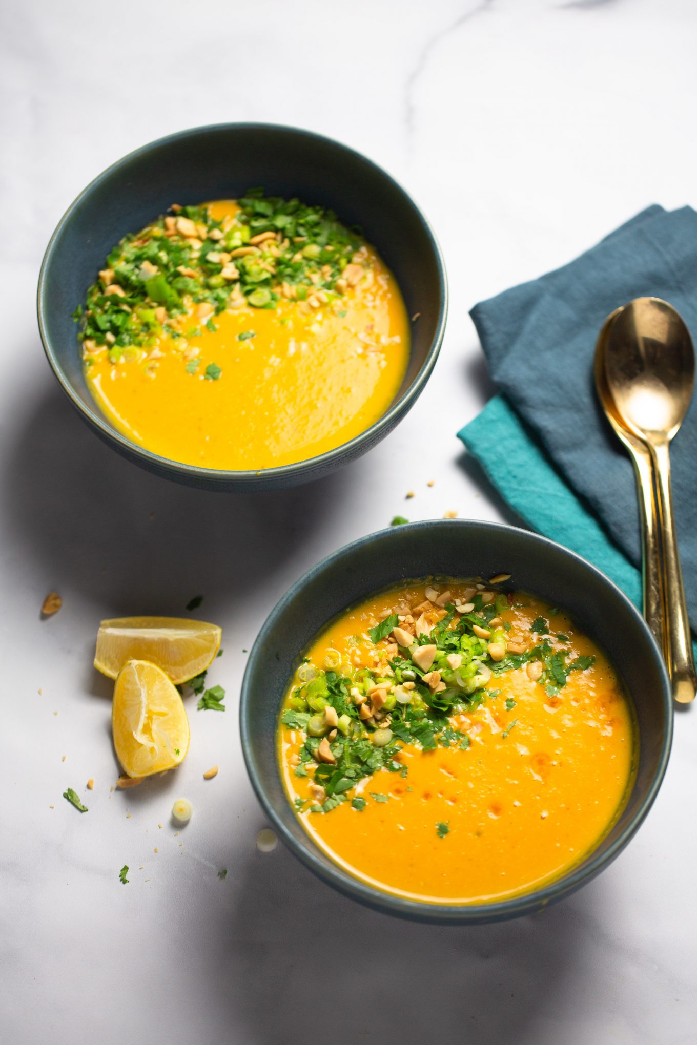 two bowls of thai soup with toppings.