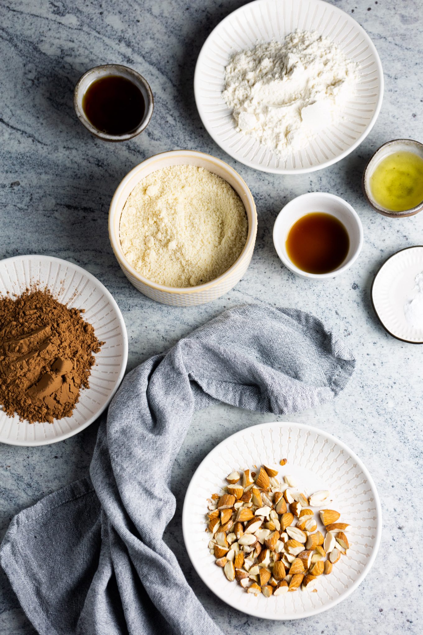 Flour, almond meal, cocoa, oil, vanilla and maple syrup measured in individual dishes.