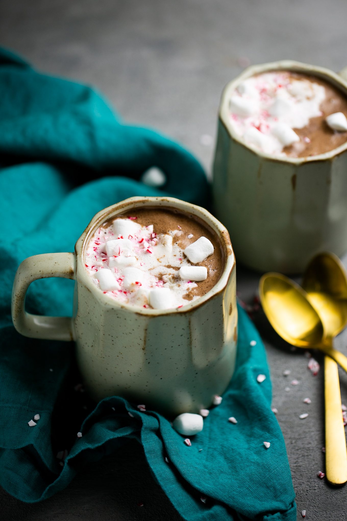 two mugs with vegan hot chocolate placed over a green napkin.