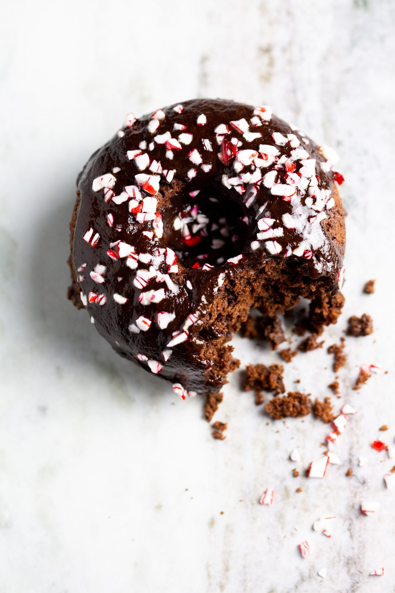 A chocolate donut with peppermint sprinkles on top.