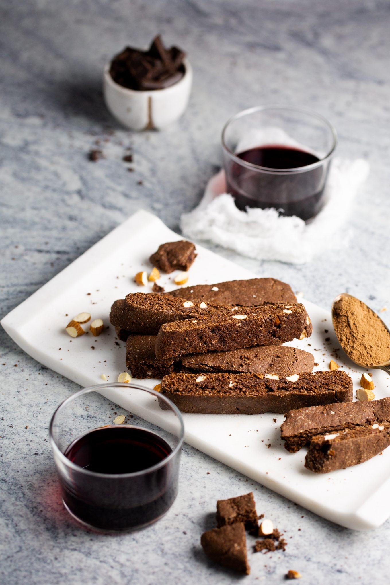 Chocolate biscotti on a white tray and a glass of red wine.