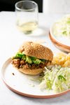 A plate with a sloppy joe sandwich and a glass of wine.