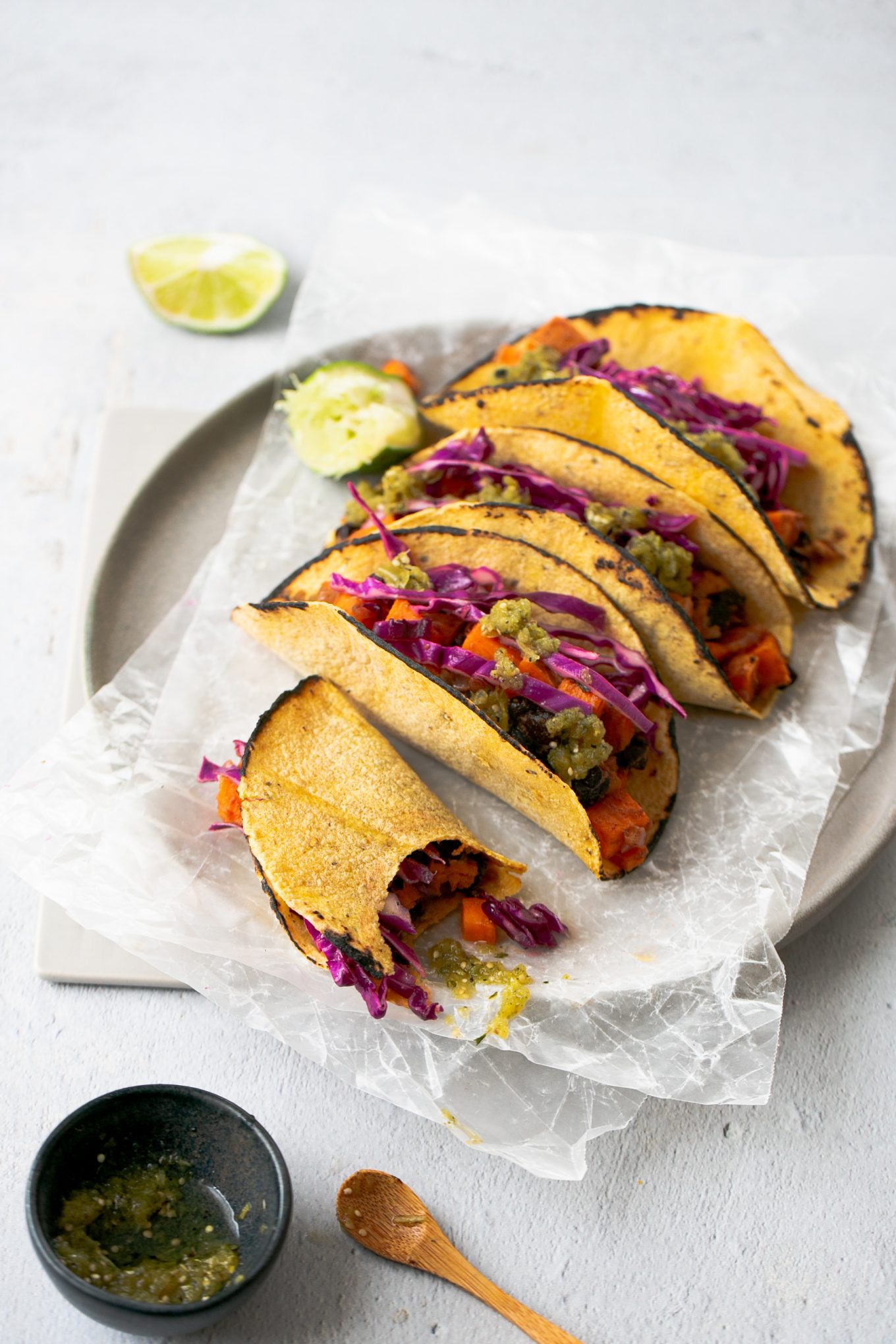 Vegan tacos with black beans and sweet potatoes topped with red cabbage and salsa verde