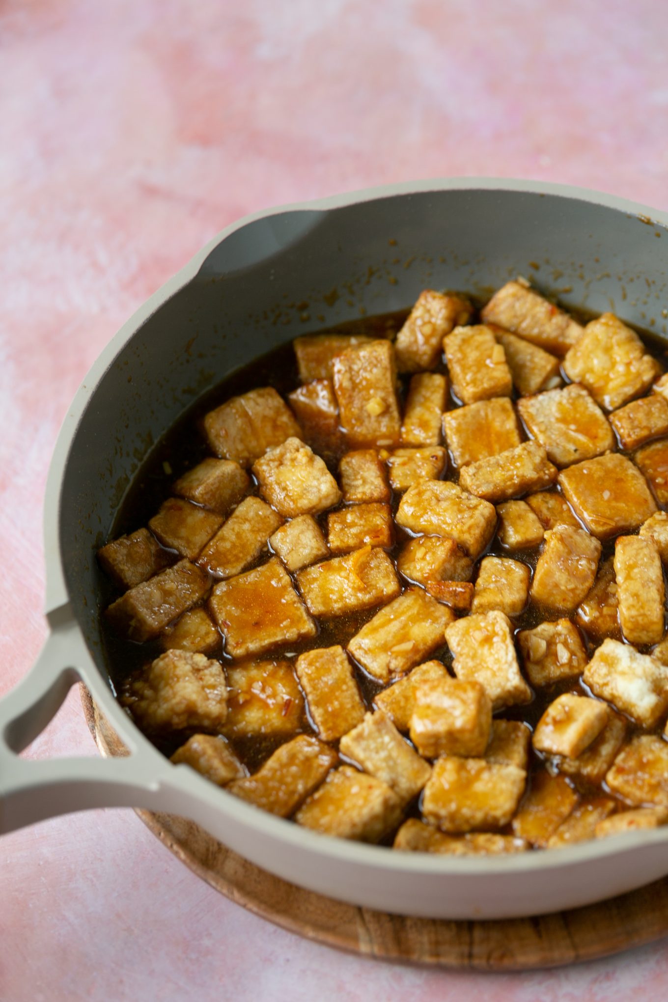 delicious crispy tofu in pan covered in orange sauce
